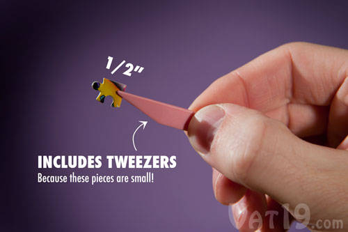 A piece from the World's Smallest Jigsaw Puzzle being held by a pair of tweezers.