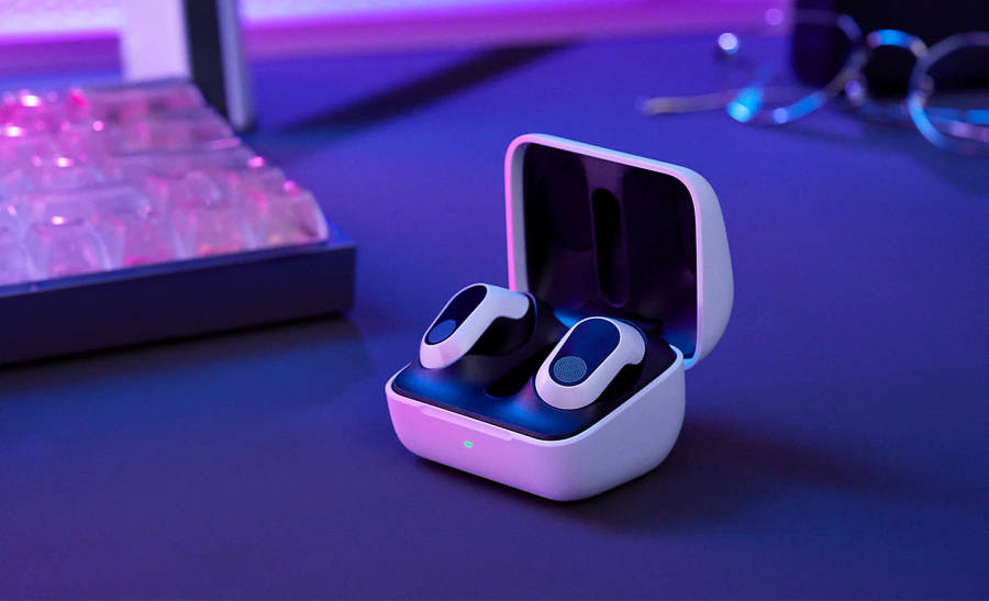 The INZONE Buds in their charging case sitting on a desk with a keyboard