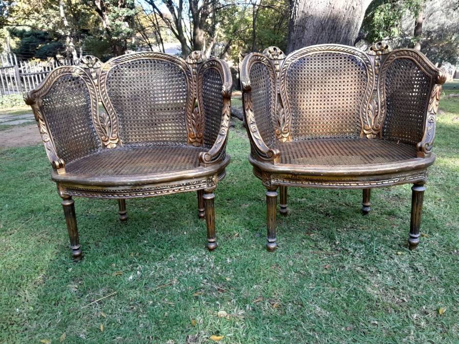 A French Louis XVI Style Pair of Ornately Carved Giltwood Rattan Bergere Chairs