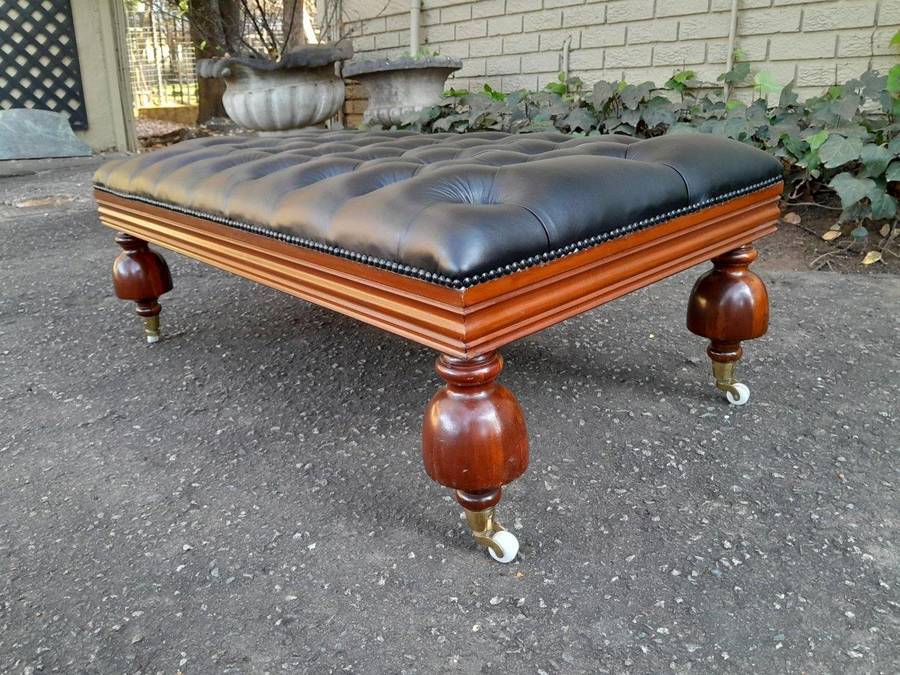 A 20th Century Ottoman With Wooden Legs On Castors Upholstered In Deep Buttoned Leather