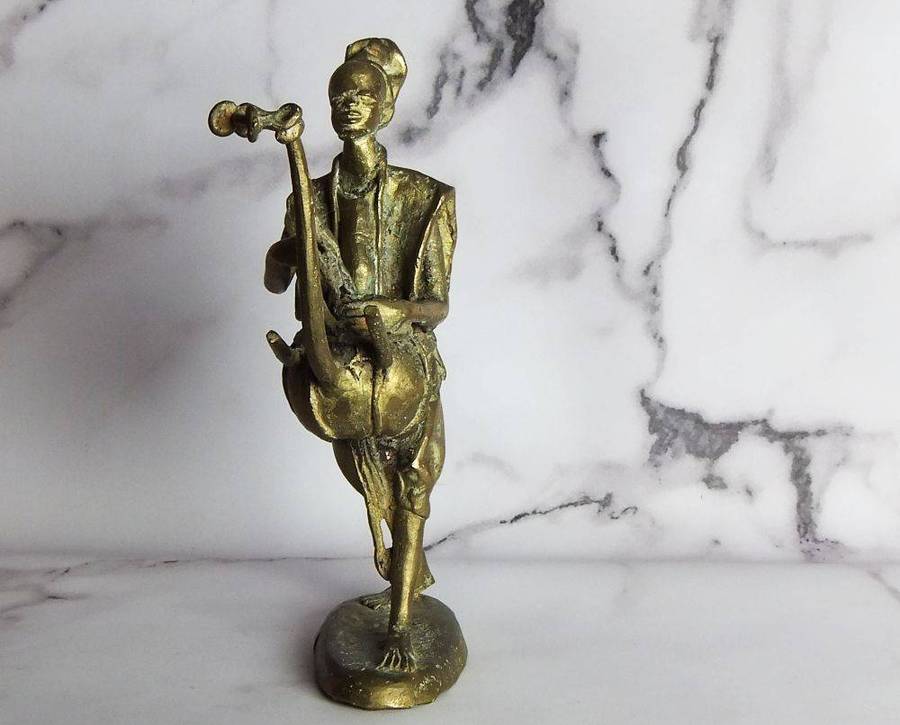 A rare mid 20th century African solid bronze statue of a tribesman with a traditional instrument