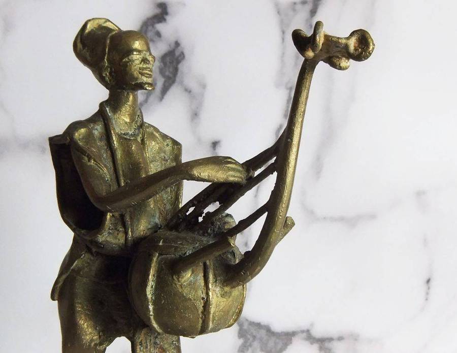 A rare mid 20th century African solid bronze statue of a tribesman with a traditional instrument