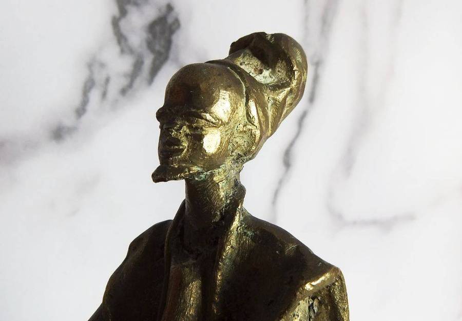 A rare mid 20th century African solid bronze statue of a tribesman with a traditional instrument