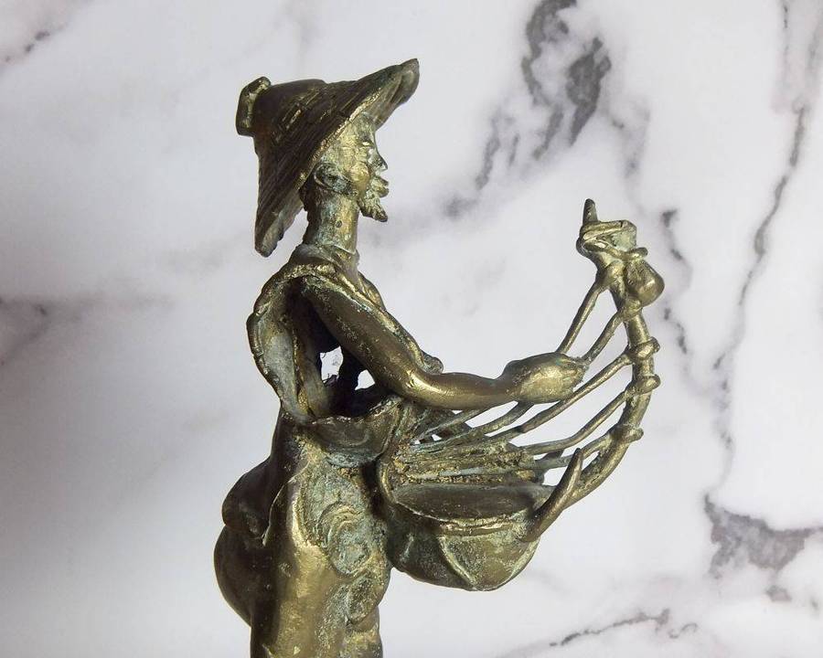 A rare mid 20th century African solid bronze statue of a tribesman with a traditional instrument