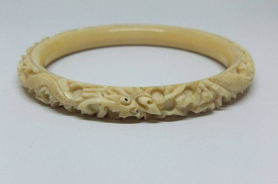 An antique 1920`s Chinese carved bone bangle with Dragon motif
