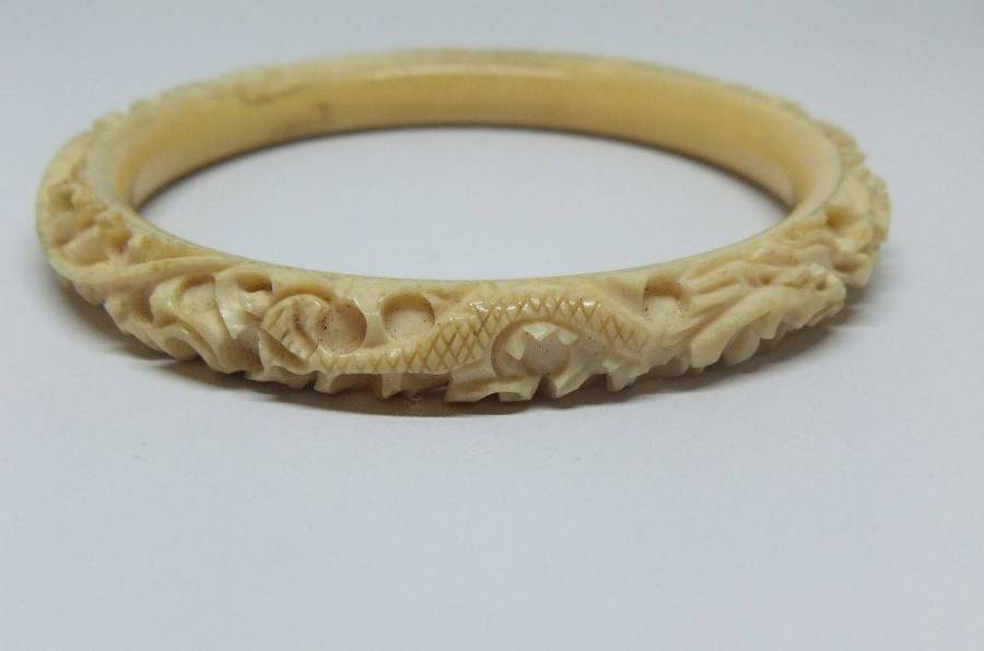 An antique 1920`s Chinese carved bone bangle with Dragon motif