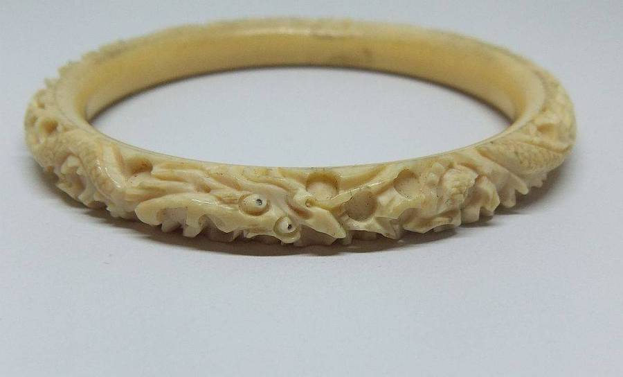 An antique 1920`s Chinese carved bone bangle with Dragon motif