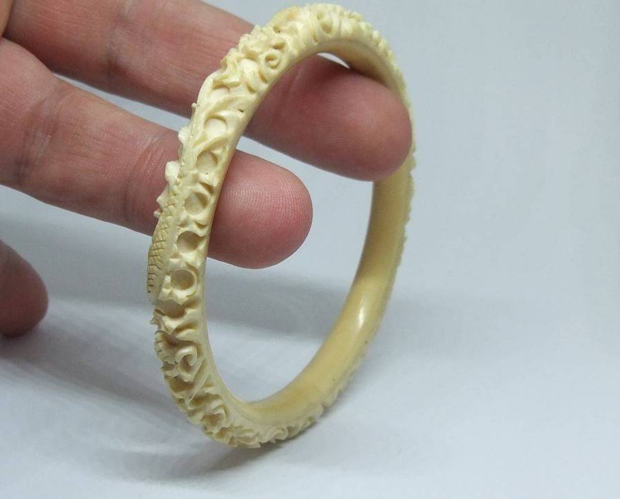 An antique 1920`s Chinese carved bone bangle with Dragon motif