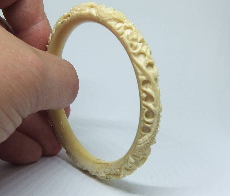 An antique 1920`s Chinese carved bone bangle with Dragon motif
