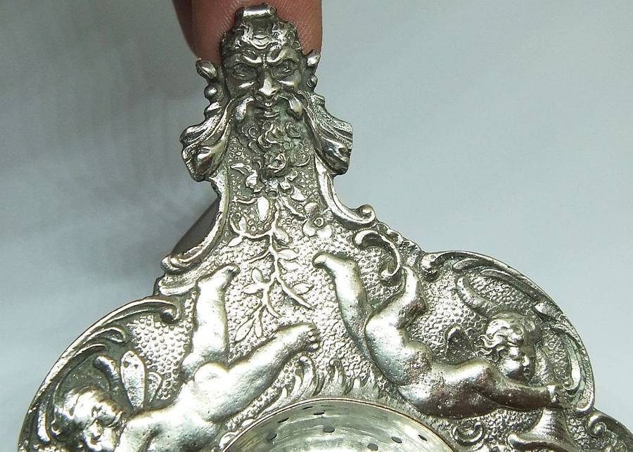 WOW !! A BEAUTIFUL ANTIQUE TEA STRAINER DECORATED WITH CHERUBS STAMPED WITH UNKNOWN MARKINGS