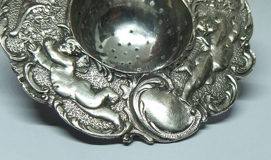 WOW !! A BEAUTIFUL ANTIQUE TEA STRAINER DECORATED WITH CHERUBS STAMPED WITH UNKNOWN MARKINGS