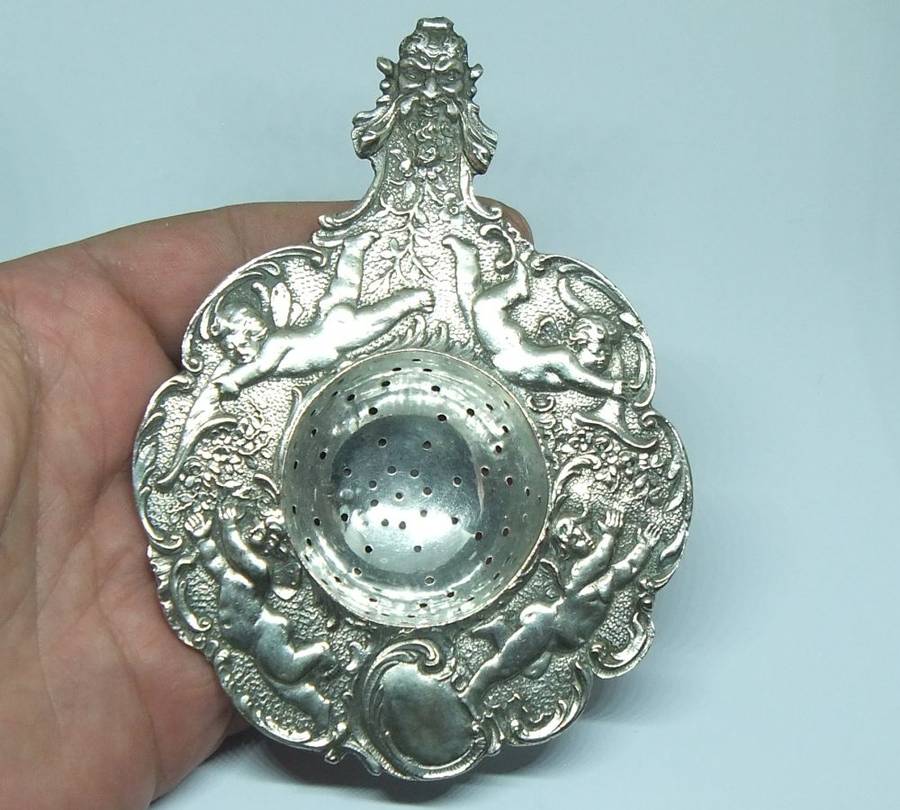 WOW !! A BEAUTIFUL ANTIQUE TEA STRAINER DECORATED WITH CHERUBS STAMPED WITH UNKNOWN MARKINGS