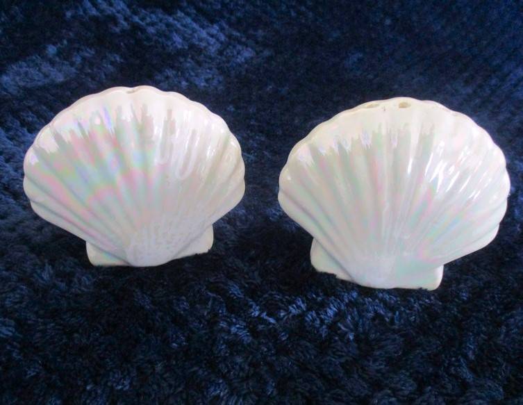 A  set of twelve pearlescent porcelain serviette rings with clam shaped salt and pepper cellars