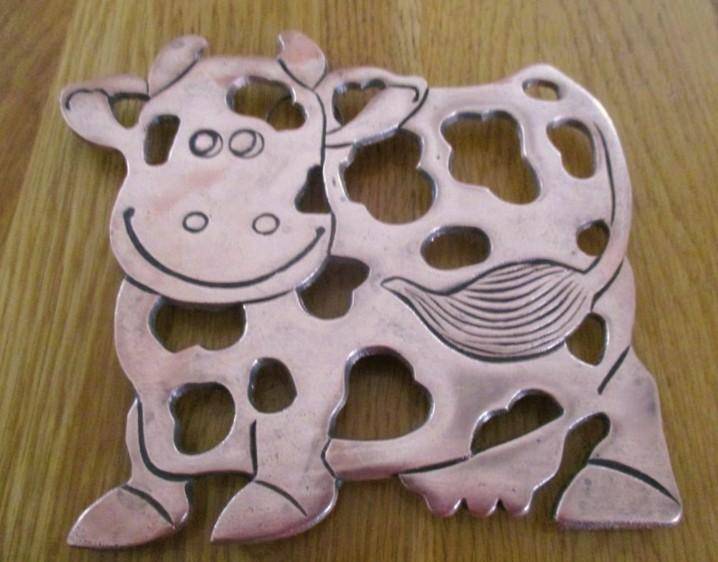A vintage 1993 copper/copper toned trivet/pot stand with cute cow design