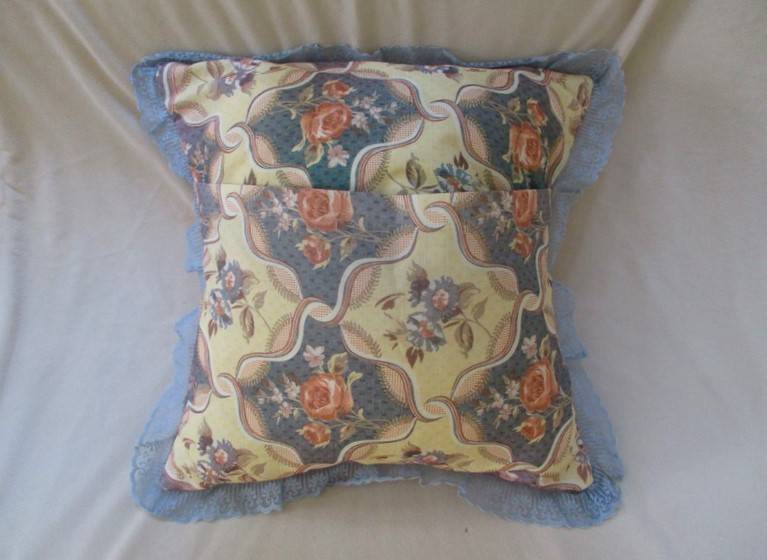 A pretty, plump cushion with floral design and lace border