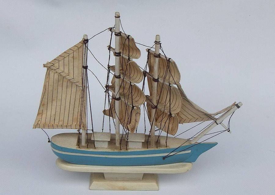 A detailed vintage wooden model of a sail ship with cloth sails