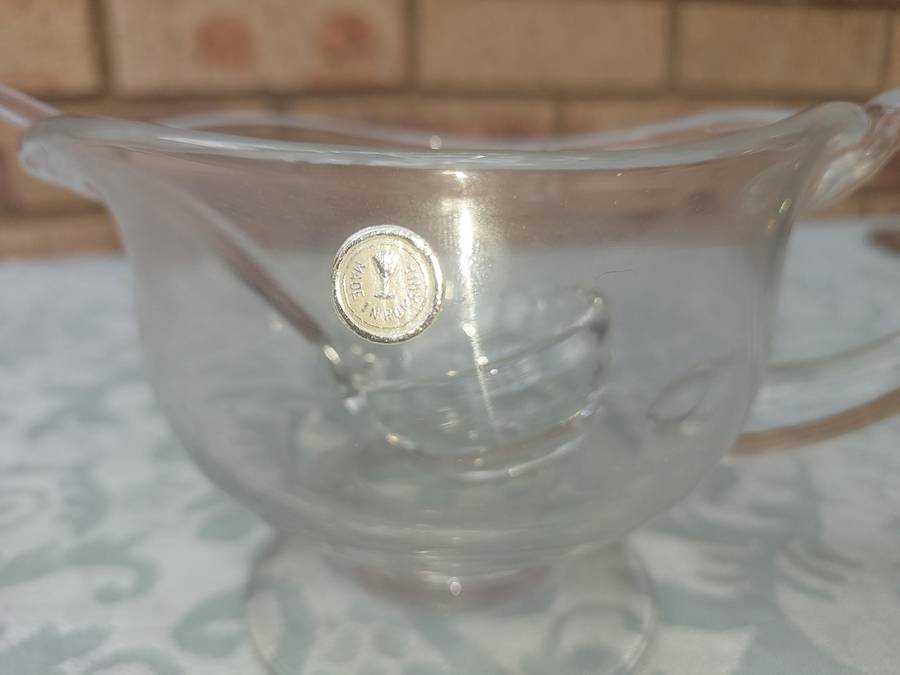A CUT GLASS SAUCE JUG AND LADLE MADE IN ROMANIA SOLD AS IS