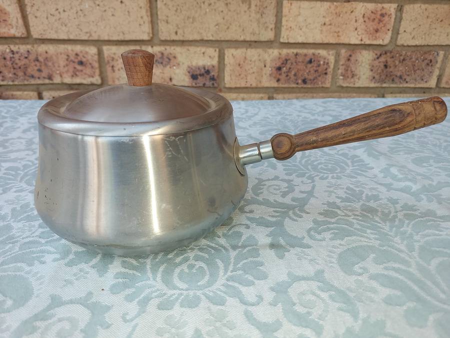 A VINTAGE SAUCE PAN WITH WOODEN HANDLE AND WARMER STAND