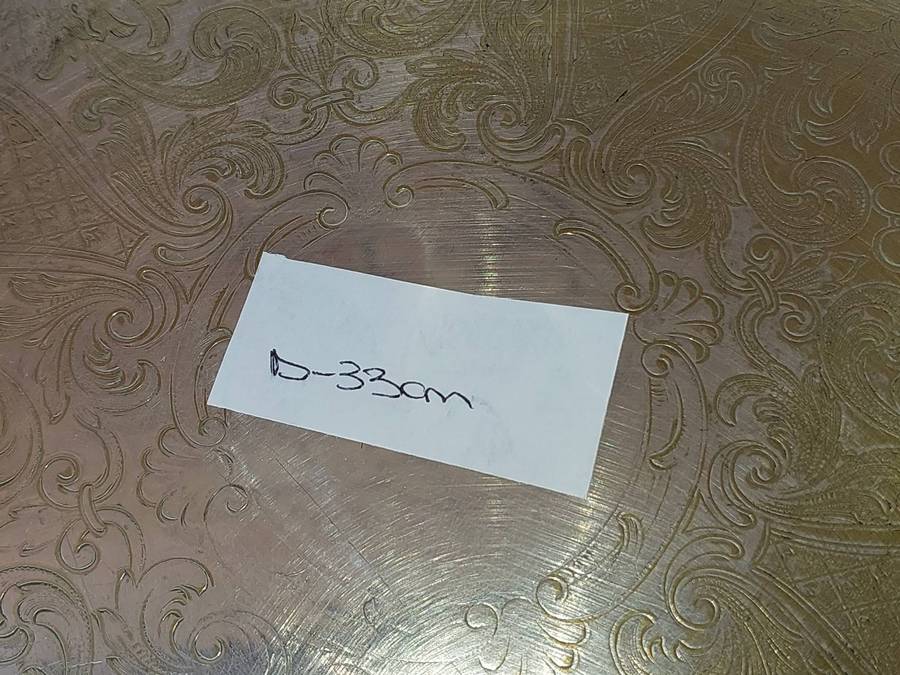 AN ORNATELY ENGRAVED SILVER PLATED SERVING TRAY SOLD AS IS