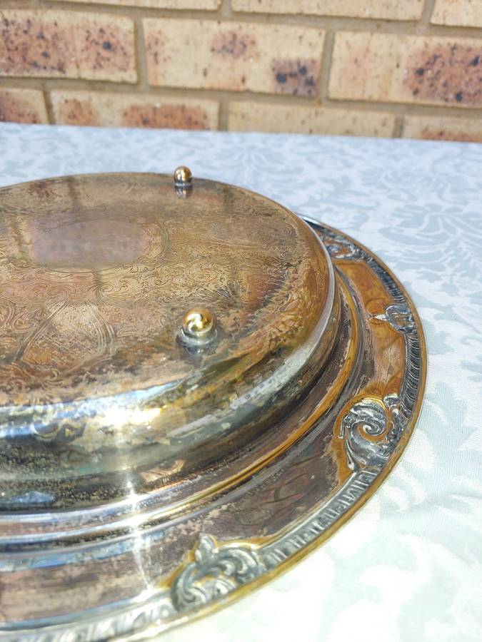 AN ORNATELY ENGRAVED SILVER PLATED SERVING TRAY SOLD AS IS