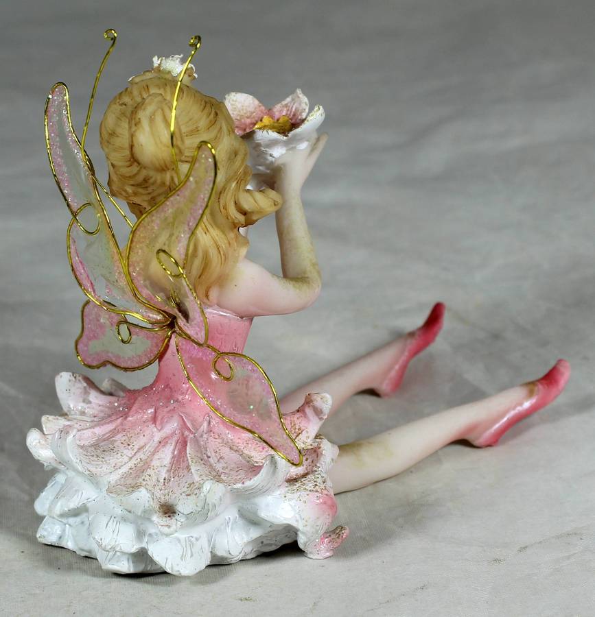 Seated ballerina in pink, holding a large flower