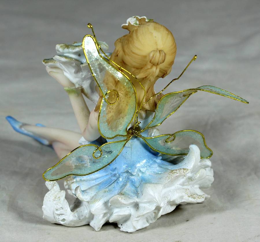 Seated ballerina in blue, holding a large flower