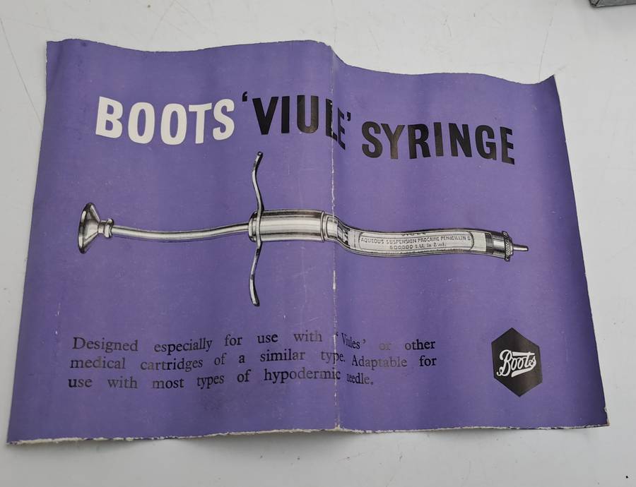 Boots viule syringe in a metal case with two glass containers with needles inside.