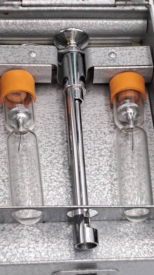 Boots viule syringe in a metal case with two glass containers with needles inside.