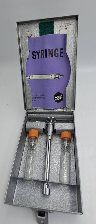 Boots viule syringe in a metal case with two glass containers with needles inside.