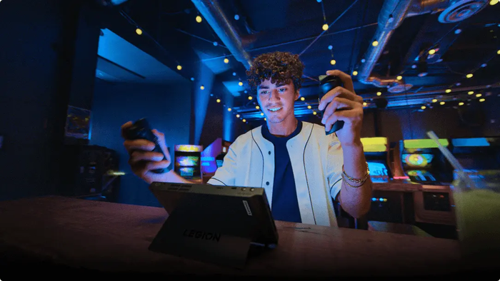 Young man sitting in front of a Legion Go in Detachable Mode, using the detachable controllers