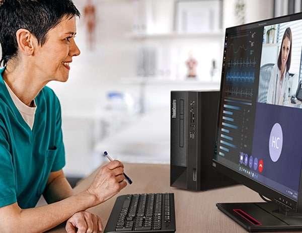 A person sits at a desk, facing right, while using the ThinkCentre Neo 50s Gen 4 SFF business PC in an office environment (monitor not included).