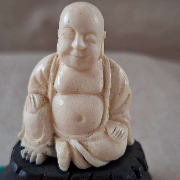 Carved buddha figurine on a wooden plinth 5.5 cms tall approx