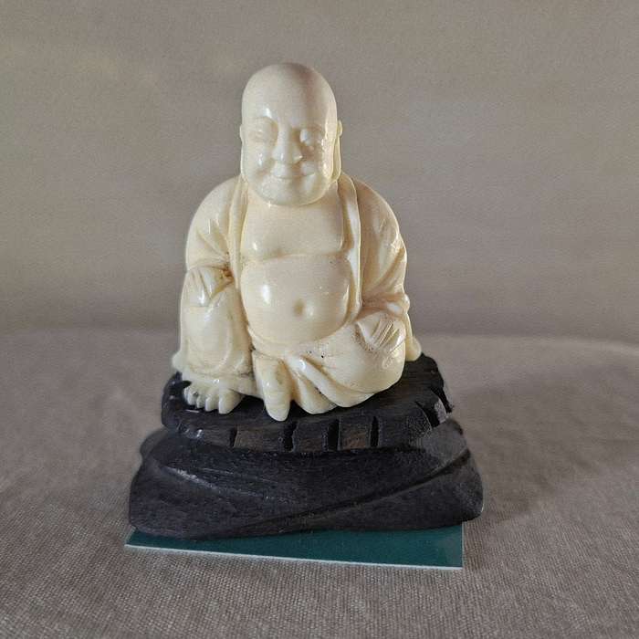 Carved buddha figurine on a wooden plinth 5.5 cms tall approx