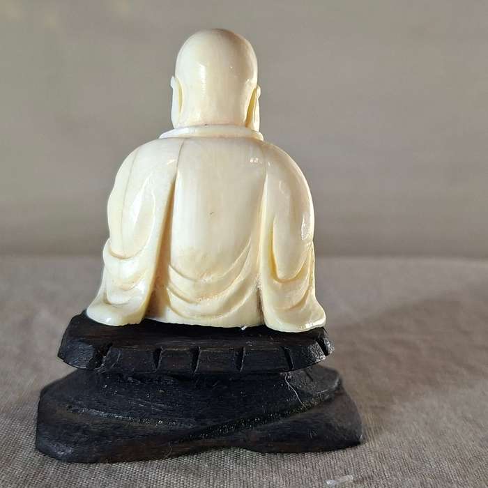 Carved buddha figurine on a wooden plinth 5.5 cms tall approx