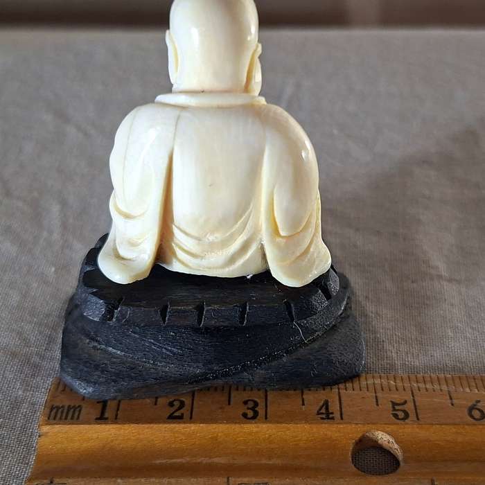 Carved buddha figurine on a wooden plinth 5.5 cms tall approx