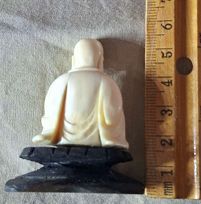 Carved buddha figurine on a wooden plinth 5.5 cms tall approx