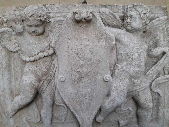 A Concrete Relief Plaque Sculpture With Putti (Cherubs) Holding A Crest