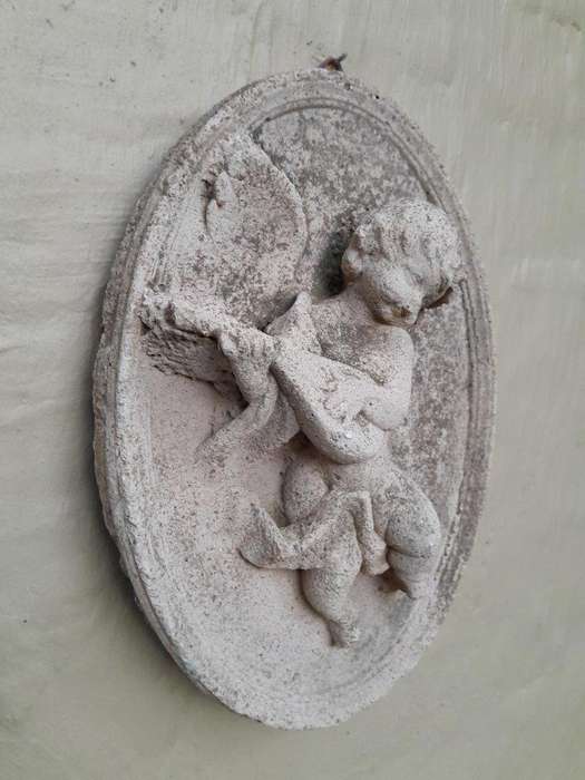 A Concrete Relief Oval Sculpture Of An Ornate Cherub Plaque