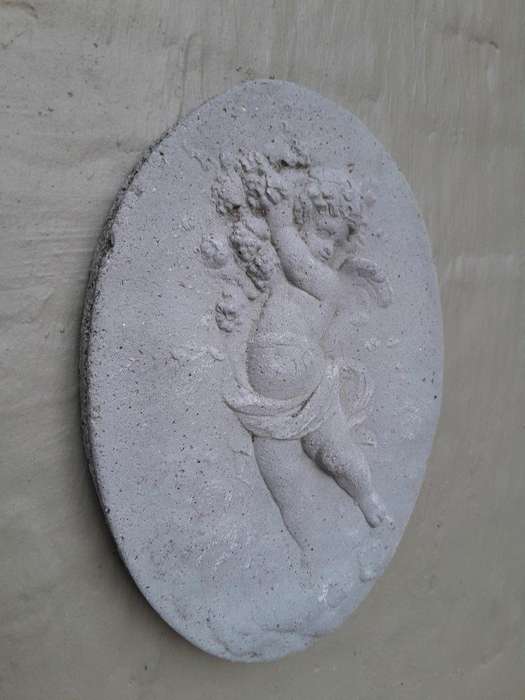 A Concrete Relief Oval Sculpture Of An Ornate Cherub Plaque