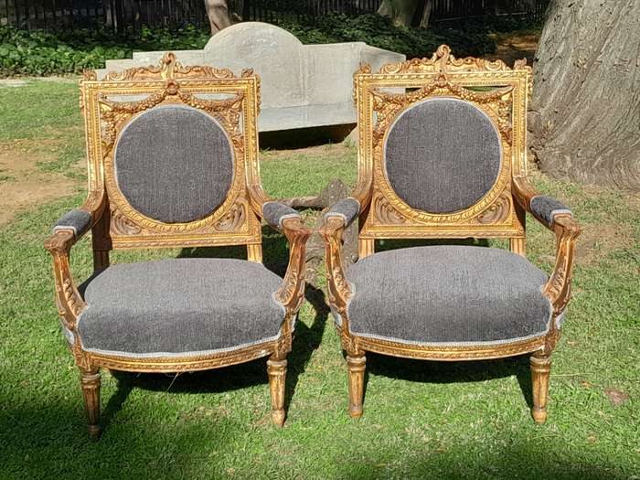 A 20th Century French Style Ornately Carved and Gilded Pair of Arm Chairs
