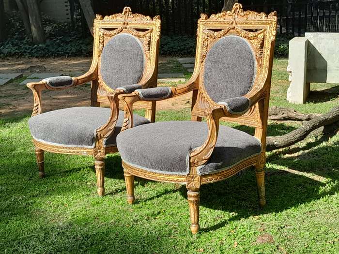 A 20th Century French Style Ornately Carved and Gilded Pair of Arm Chairs