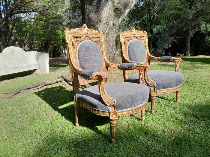 A 20th Century French Style Ornately Carved and Gilded Pair of Arm Chairs