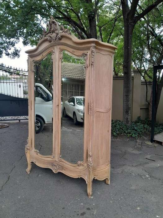 An Antique French Heavily Carved Oakd Two Door Armoire with Bevelled Mirrors and Four Shelves