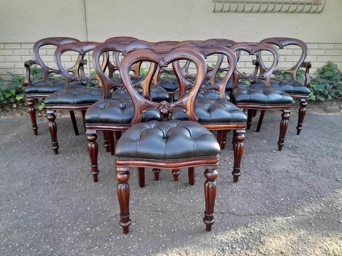 A 20th Century Set Of Twelve Teak Wood Bustle Back Chairs Comprising A Pair Of Carvers / Armchair...