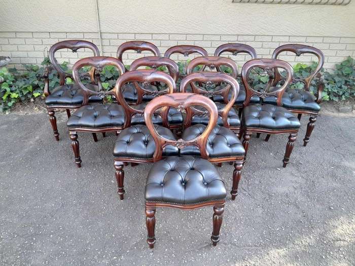 A 20th Century Set Of Twelve Teak Wood Bustle Back Chairs Comprising A Pair Of Carvers / Armchair...