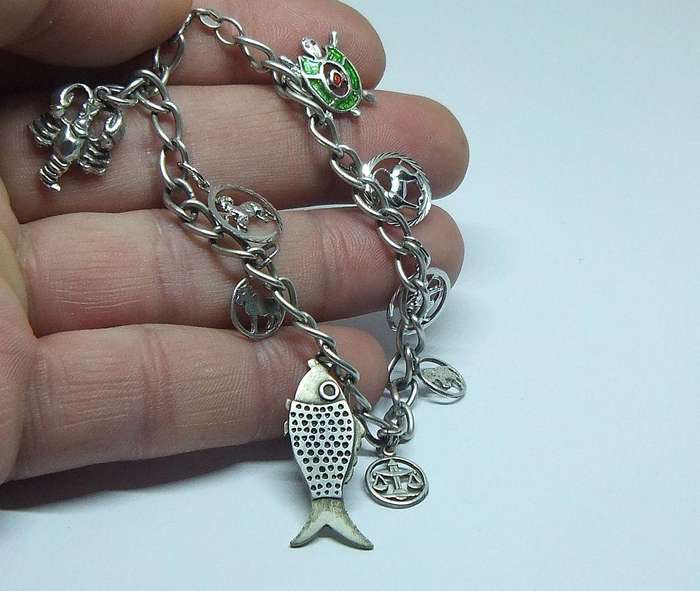 A VERY COOL VINTAGE STERLING SILVER CHARM BRACELET WITH VARIOUS DEGREES OF SILVER CHARMS , JUST LOOK