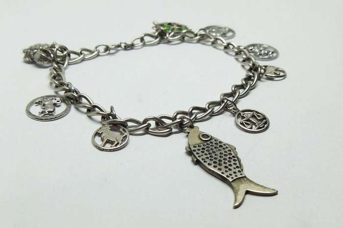 A VERY COOL VINTAGE STERLING SILVER CHARM BRACELET WITH VARIOUS DEGREES OF SILVER CHARMS , JUST LOOK