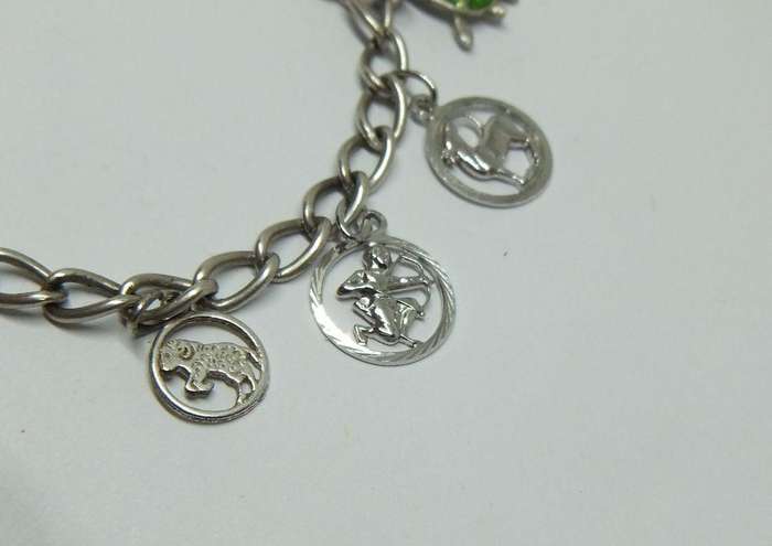 A VERY COOL VINTAGE STERLING SILVER CHARM BRACELET WITH VARIOUS DEGREES OF SILVER CHARMS , JUST LOOK