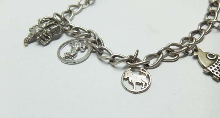 A VERY COOL VINTAGE STERLING SILVER CHARM BRACELET WITH VARIOUS DEGREES OF SILVER CHARMS , JUST LOOK