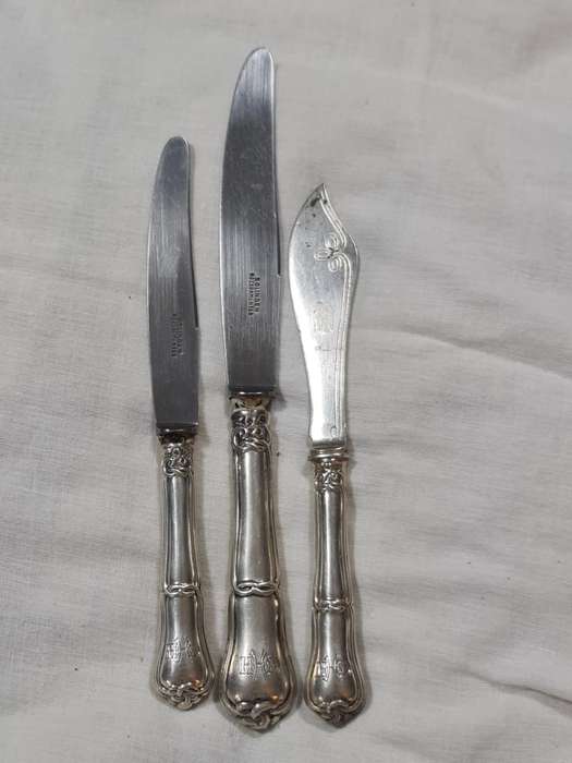 Three knifes with ornate handles and monogram on handle.